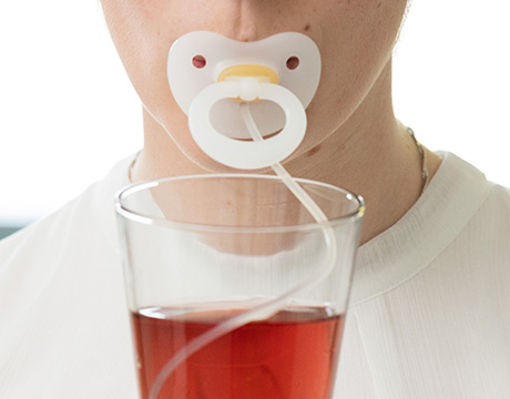 Person mit medizinischem Trinknuckel im Mund.