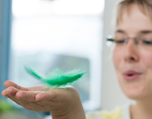 Frau hält eine Federkugel in der Hand.
