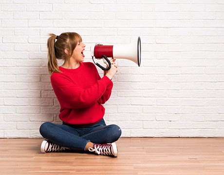 Frau schreit in ein Megaphon.