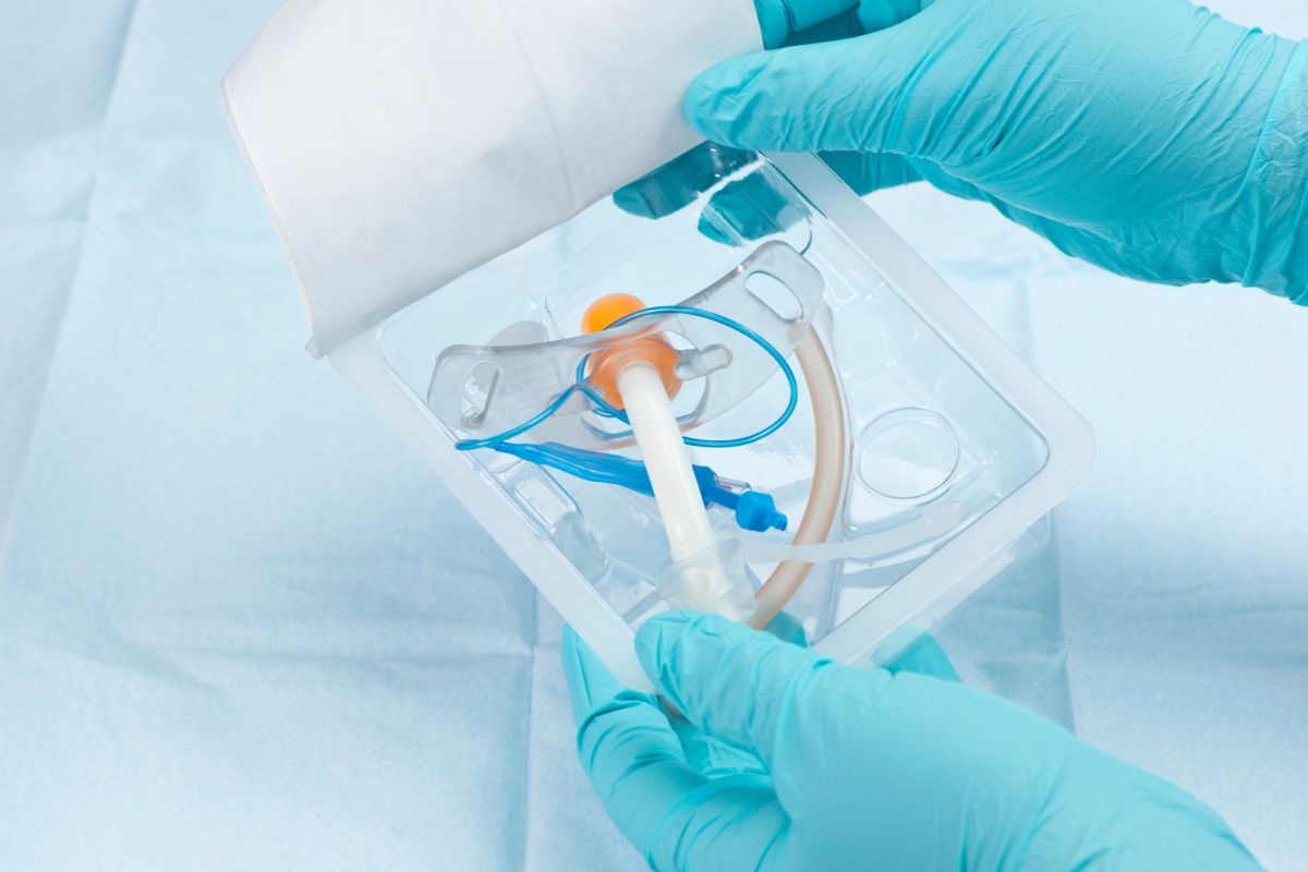 Trachealkanüle wird von zwei behandschuhten Händen ausgepackt.