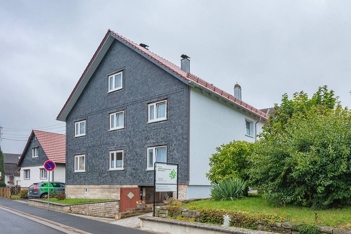 Haus in einer Wohnstraße mit Garten und Autos.