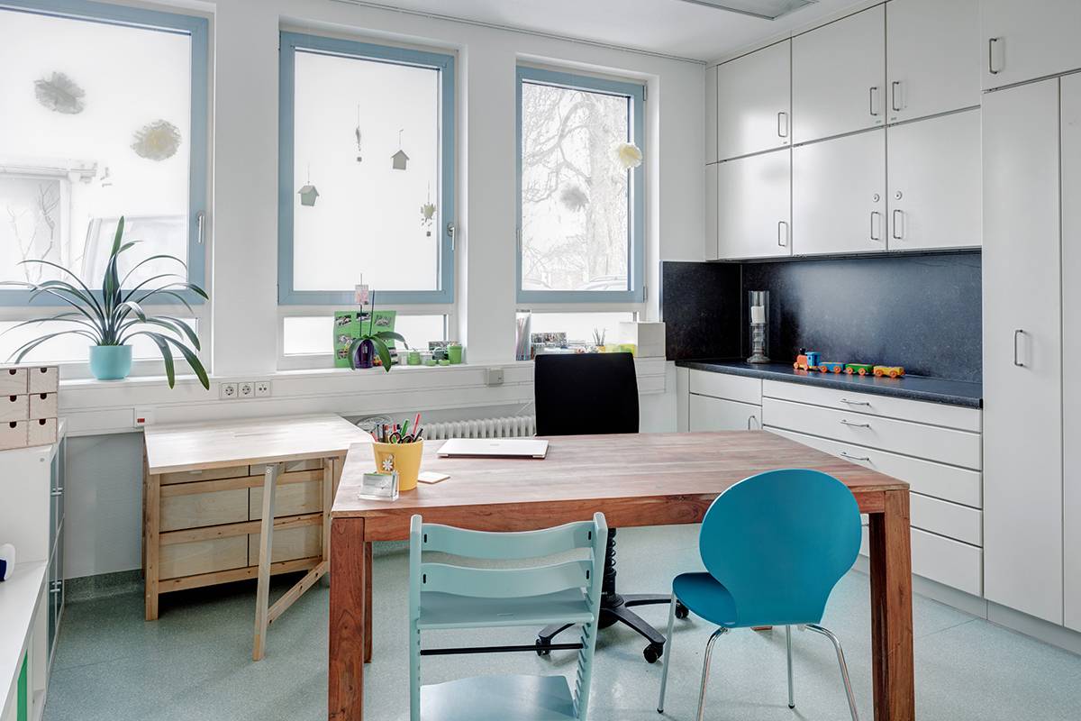 Büro mit blauen und hellblauen Stühlen, weißen Schränken.