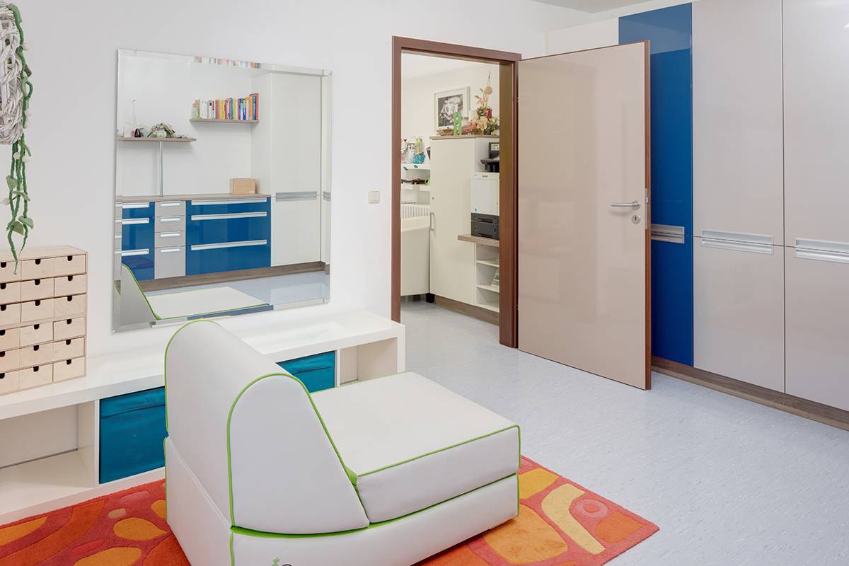 Raum mit Sitzgelegenheit, Spiegel und offener Tür.