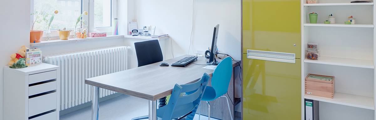 Helles Büro mit blauem Stuhl und Computer.