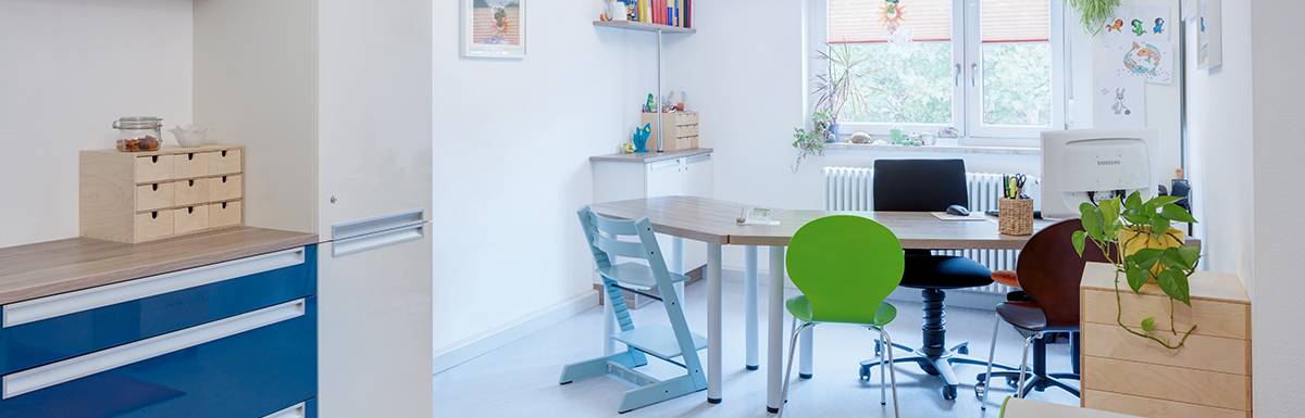 Büro mit bunten Stühlen und Pflanzen am Fenster.