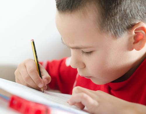 Junge beim Schreiben mit Bleistift.